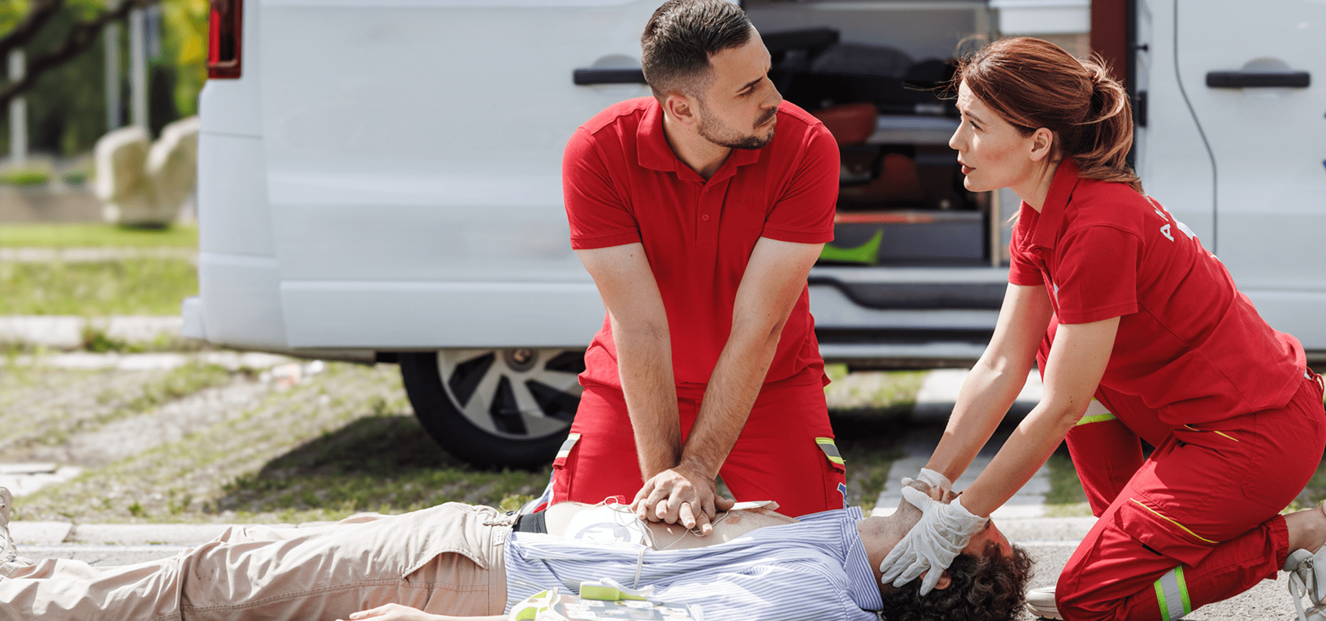 Paramedics performing CPR on a patient outdoors.