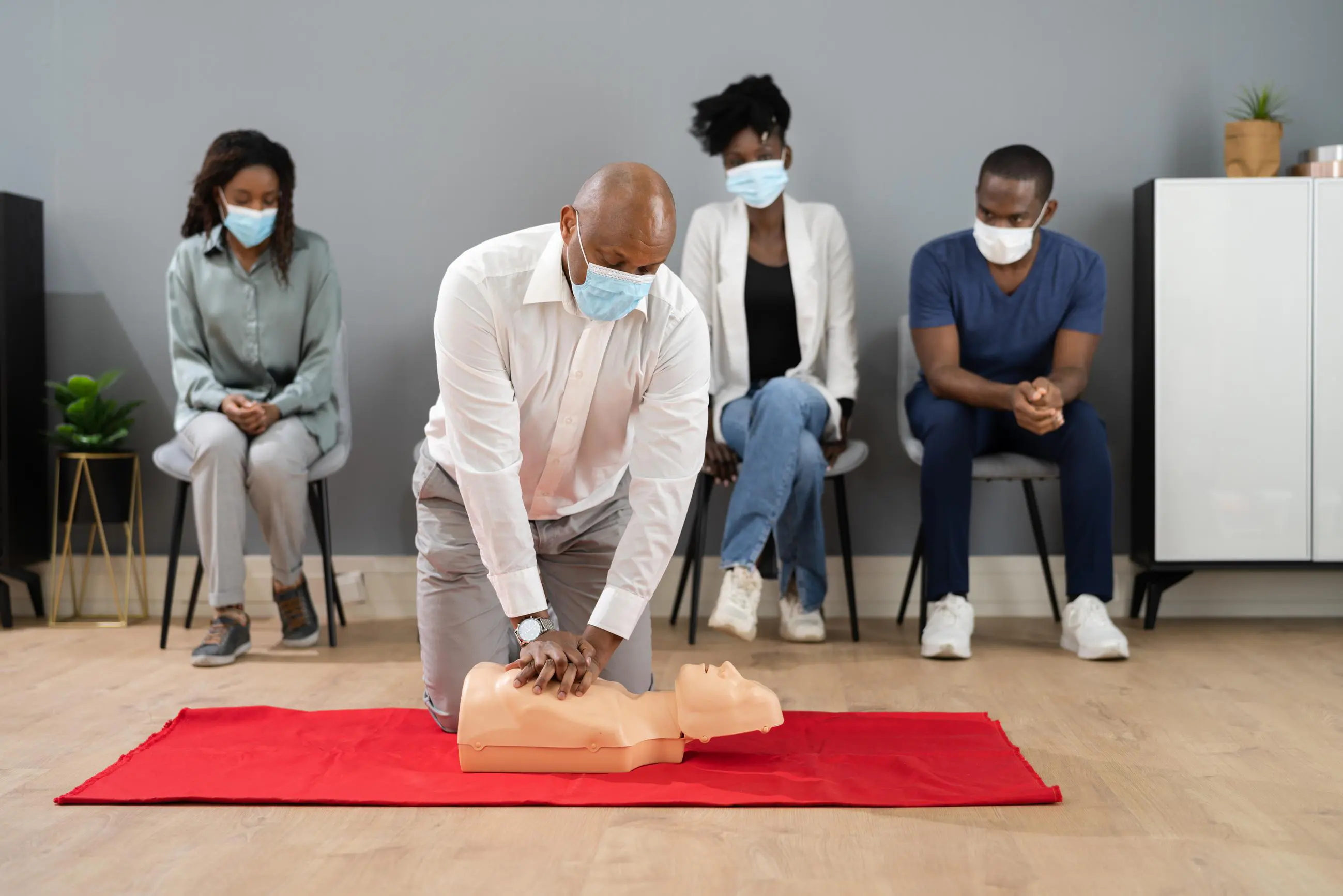 Man demonstrating CPR on dummy in class.