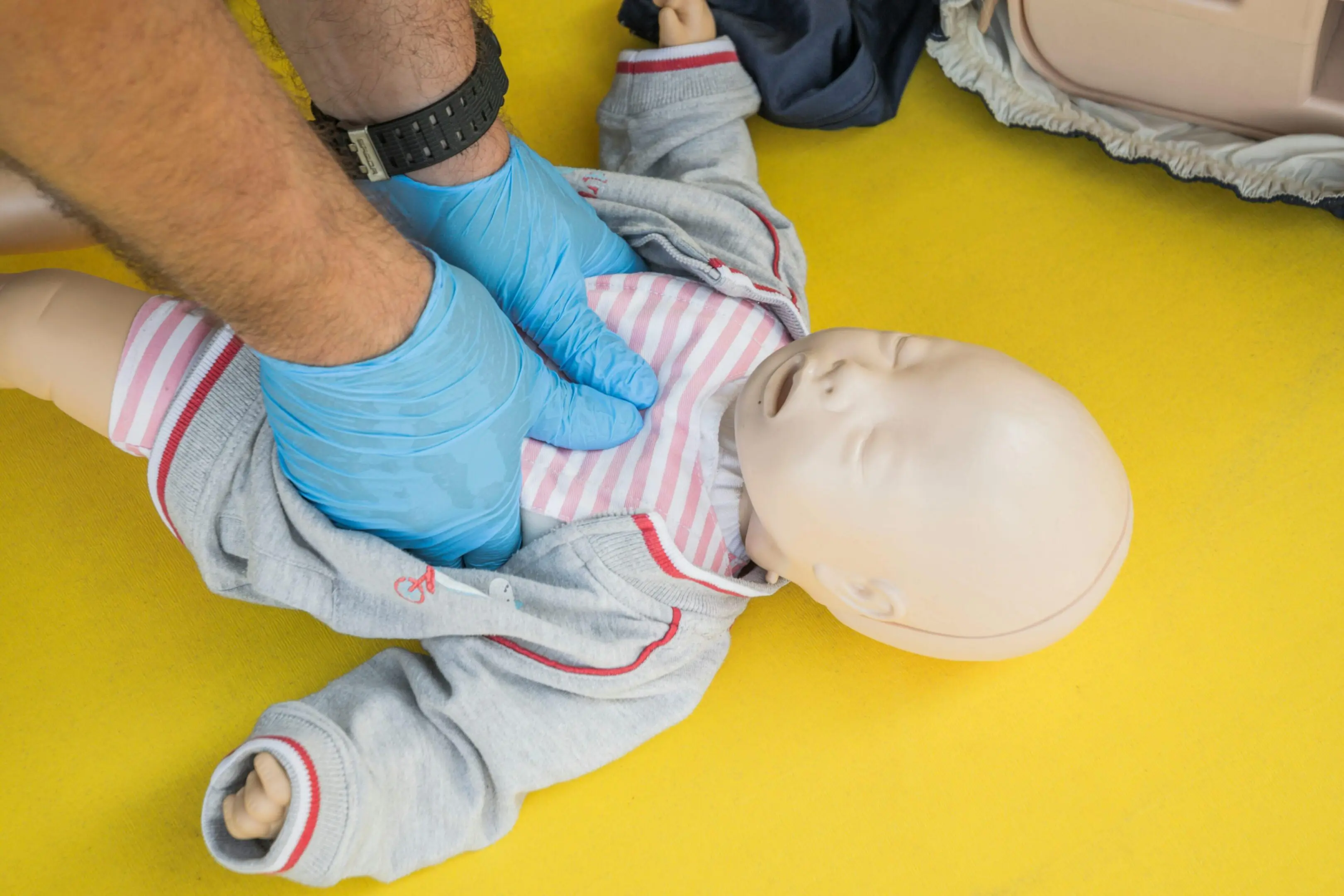 Person performing infant CPR on a baby mannequin.